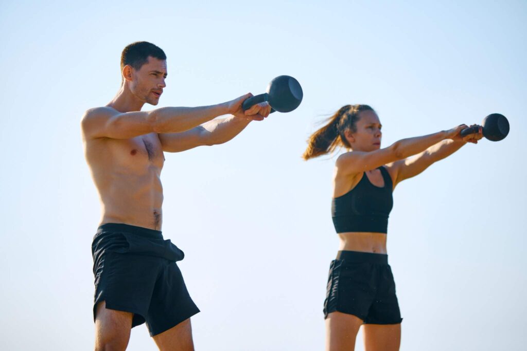 A man and woman doing kettlebell swing