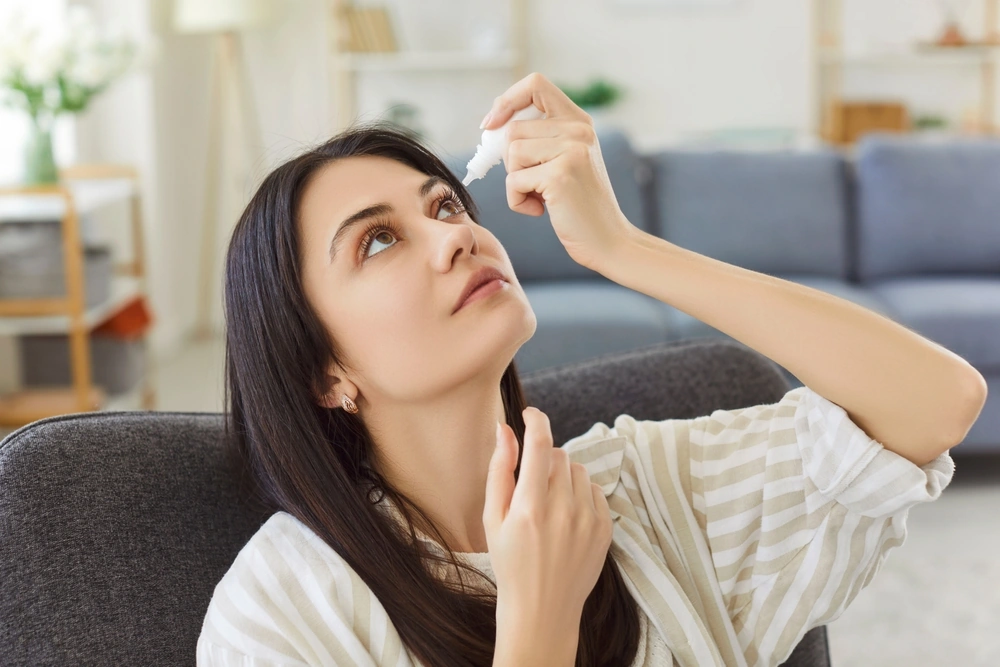 A lady applying artificial tears to relieve eye strain