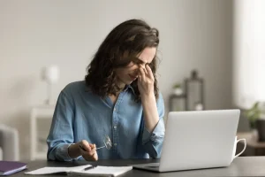 A woman suffering from eye strain for staring at her phone for too long