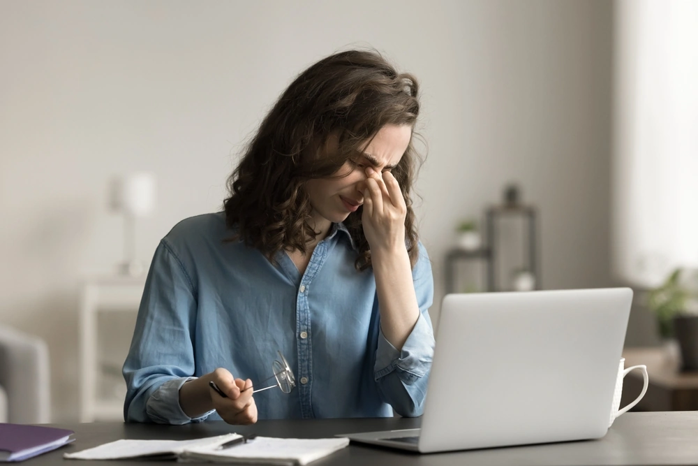 A woman suffering from eye strain for staring at her phone for too long