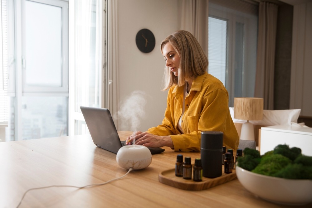 Woman working on a laptop from home near the humidifier.