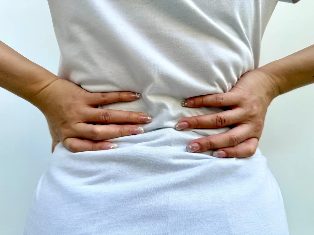 A woman pressing her back, possibly due to posture imbalance